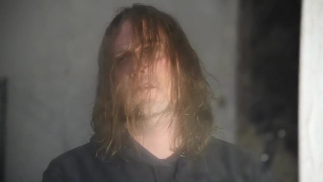 Depressed and angry man is sitting in front of his reflection in an old abandoned house