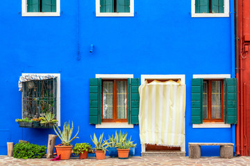 Blue colored house with flowers and bench. Colorful houses in Burano island near Venice, Italy. Venice postcard. Famous place for european tourism and travel