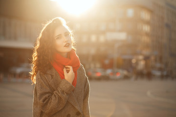 Street portrait of fabulous brunette model with wavy hair posing in soft evening backlight. Space for text