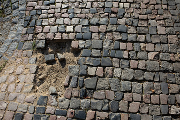 Crashed sidewalk paved with granite stones in sunny day