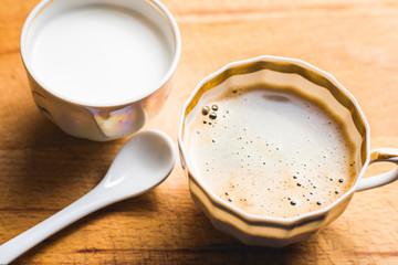 A cup of hot coffee with milk near it