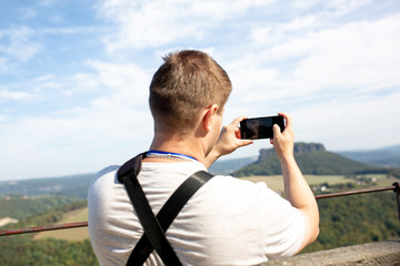 Man uses his mobilephone outdoor,taking a photo in the landscape park