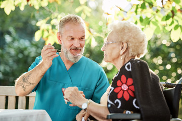 Pfleger hilft Seniorin beim essen eines Nachtischs
