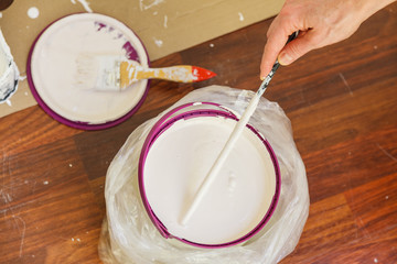 Person mixing white paint in bucket.