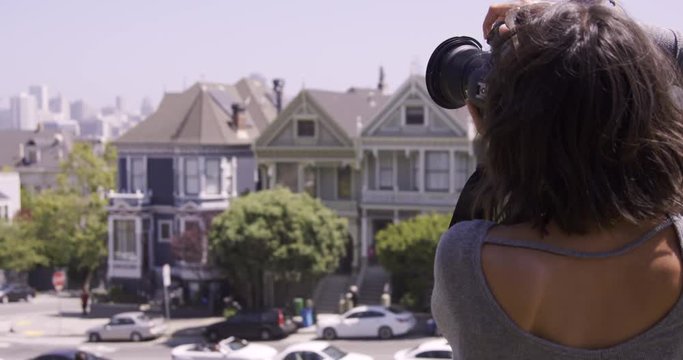 Stylish Female photographer taking photos of houses in front of city