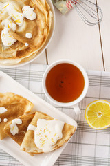 Homemade lemon crepes or blini with creamy sauce and tea.