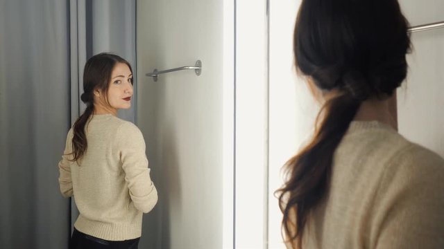 The girl measures the clothes in a fitting room