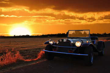 Antique cabriolet car in a landscape and sunset.