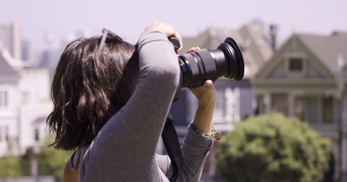 Stylish Female photographer takes photo of city scape - side profile