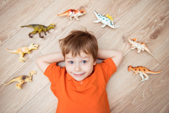 Little boy lying on the floor with a collection of dinosaurs