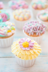 Many sweet birthday cupcakes with flowers and butter cream