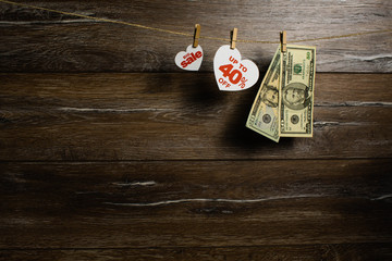 Cash of dollars hang on string next to hearts with 40 percent for big sale on wooden background. Sale on Valentine's.