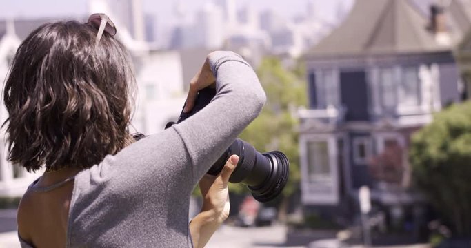 Stylish Female photographer taking photos in city - reviews photo on camera