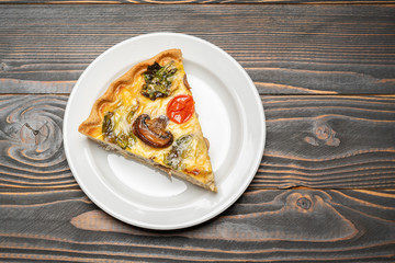 Slice of traditonal homemade spinach chicken quiche tart or pie on plate