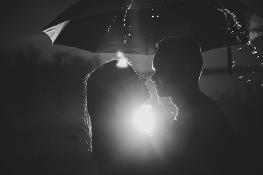 black white photo young man and woman under an umbrella and rain