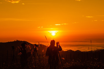 silhouette landscape at morning time tourist take pictures of the sunrise and mist on the mountain