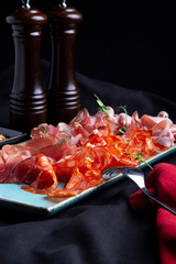 assorted cold meat, prosciutto, slices ham, beef jerky, salami, meat and mustard on black...