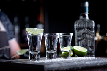 Barman pouring hard spirit into small glasses such as alcoholic shots of tequila or strong drink
