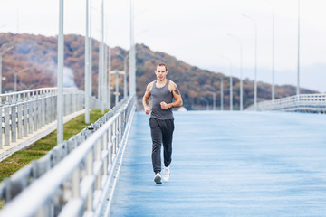 Nice tall young male runner runs through a scenic nature during a morning jog. Concept of weight loss and cardio. Place for your advertising content