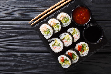 Freshly made rolls with various fillings served with soy and chili sauces close-up on a slate board. horizontal top view