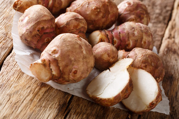 Fresh raw Jerusalem artichoke or topinambur on a paper on the wooden table