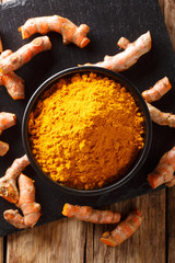 Fresh turmeric spice in a bowl and root close-up. Vertical top view
