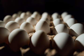 Top view of opened box with eggs on black background. Fresh chicken eggs closeup