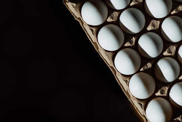 Top view of opened box with eggs on black background. Fresh chicken eggs closeup