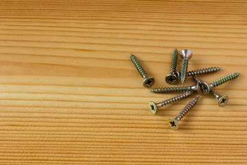 Close-up on screws, metal screws, iron screws, wood screws on wooden board