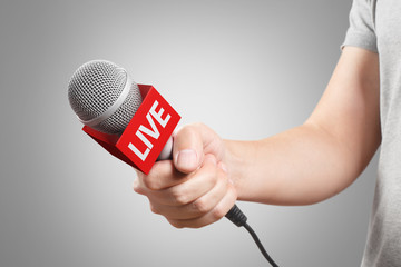 Male hand holding a microphone, isolated on grey background