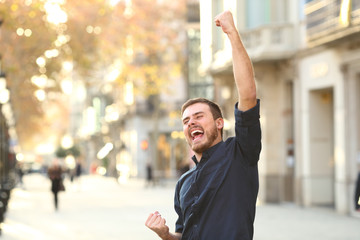 Excited man raising arms celebrating sucess