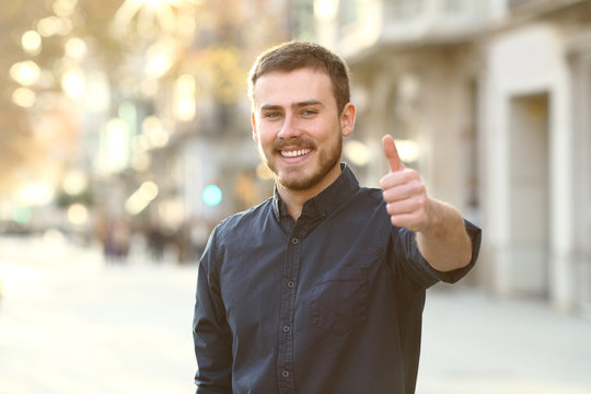 Happy man in the street gesturing thumbs up