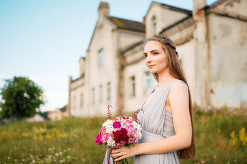 Fototapeta premium Happy bride in beautiful white dress posing with bouquet of flowers on summer day. Wedding street photo session. Beautiful cheerful lifestyle portrait of bride
