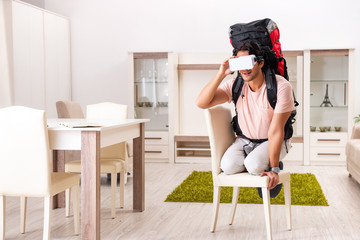 Young male tourist with virtual glasses preparing for trip 