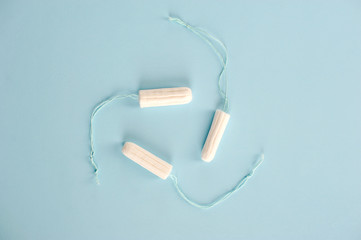 Hygienic tampons on a blue background. Three tampons of varying absorbency: normal, super, super plus. View from above.