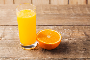 Fresh orange juice with slice of fresh orange on wooden table