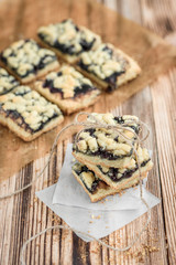 Shortbread cookies with blueberry jam on baking paper on wooden background. 