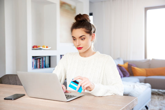 Woman shopping online with her credit card while sitting in front of laptop