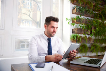 Fototapeta na wymiar Businessman working on digital tablet while sitting at office desk