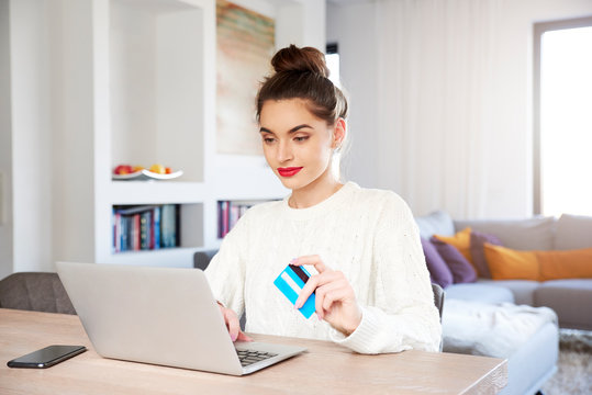Woman shopping online with her credit card while sitting in front of laptop