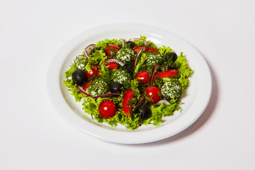 Italian cheese balls salad with tomatoes and fresh vegetables on the plate. Isolated on the white background
