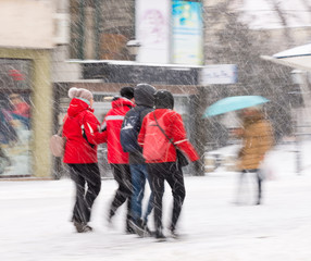 Busy city people going along the street in winter snowy day