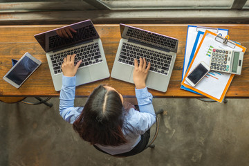 Fototapeta na wymiar High angle view of businesswoman working on two laptops