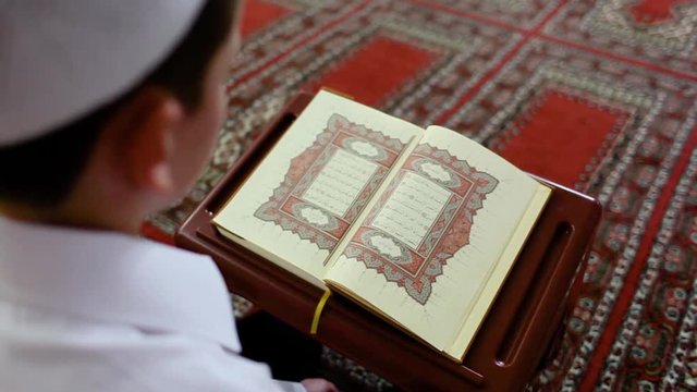 Rear shot of boy reading Quran, no face
