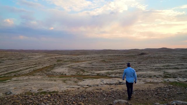 Man walking alone in vast valley, mountain landscape, cliffs