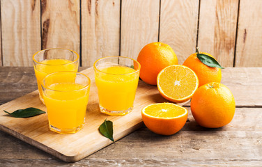 Orange juice. Glasses of orange juice and fruits against wooden background
