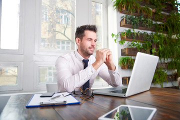 Businessman sitting in front of laptop and thinking