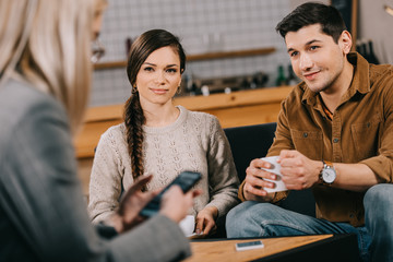 selective focus of friends looking at woman with smartphone