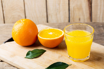 Fresh orange juice and oranges on wooden table