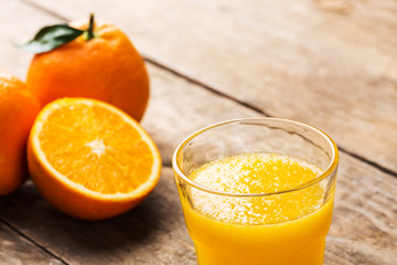 Fresh orange juice and oranges on wooden table